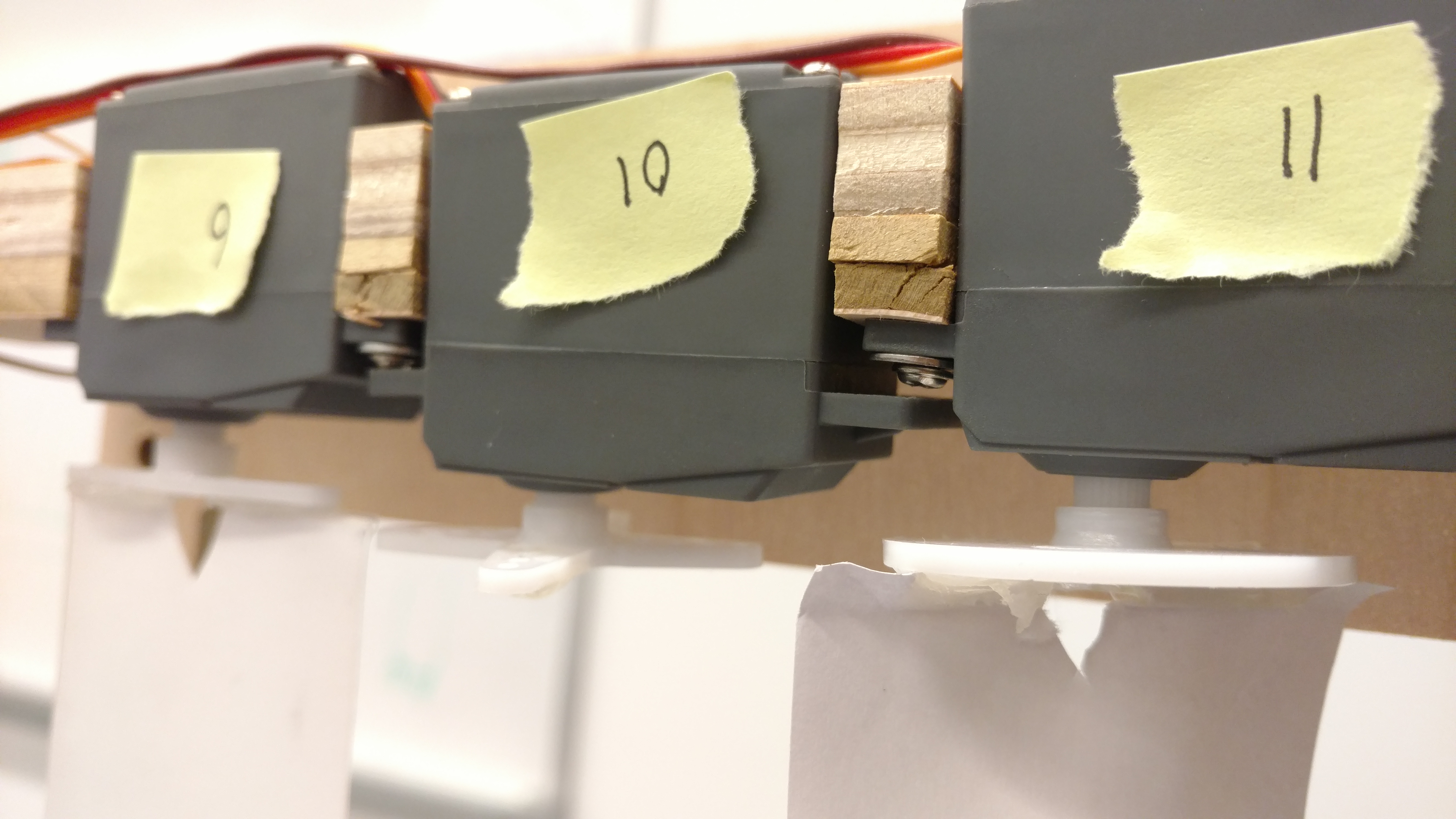 A close up of three of our servos with sticky notes that tell which pin they attach to